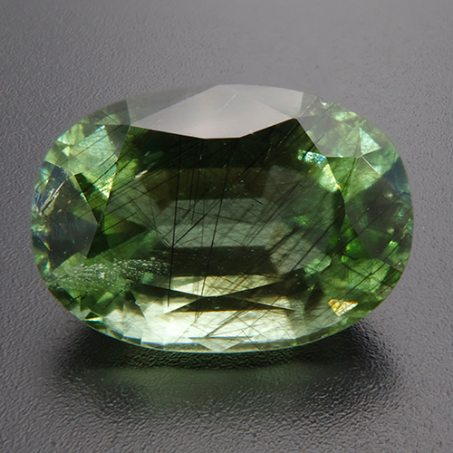 Peridot from Pakistan. 12.34 Carat. A plethora of fine ludwigite needles is proof of Pakistani origin and gives this beautiful specimen its unusual bluish green colour. For gem connoiseurs, aficionados and collectors.